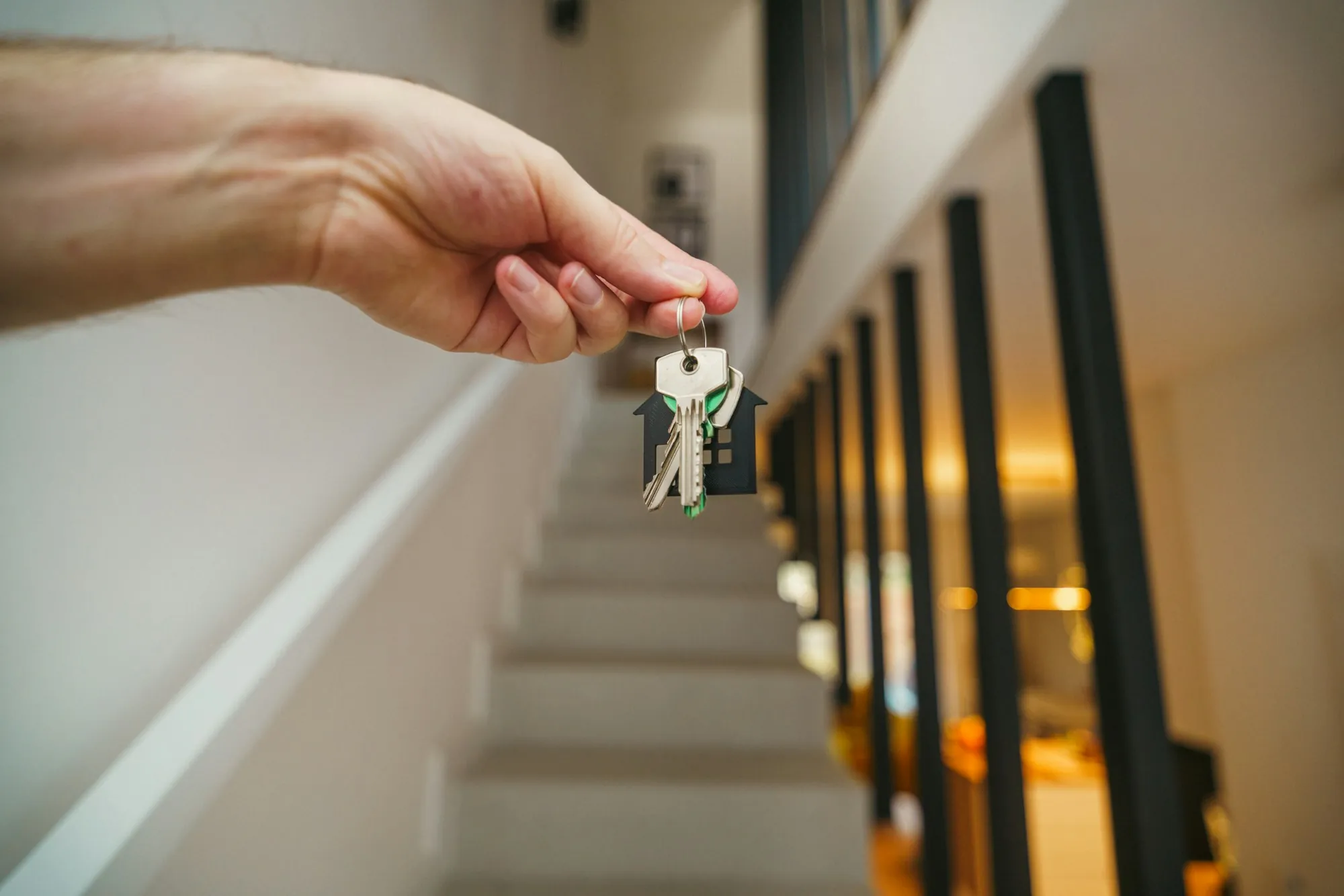 Hand holding keys beside a staircase